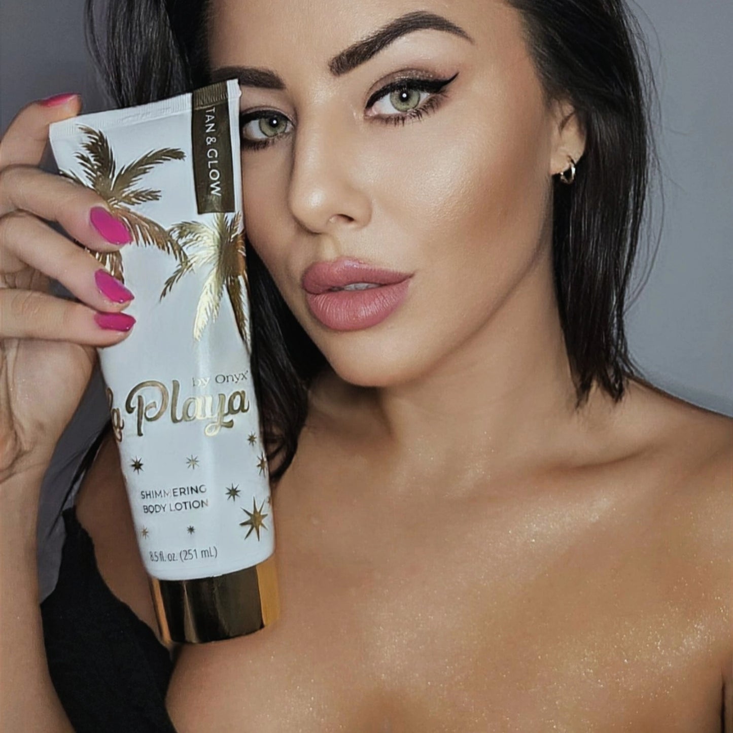 Frau hält Onyx La Playa Glow Bodylotion und zeigt glitzernde Haut am Oberkörper