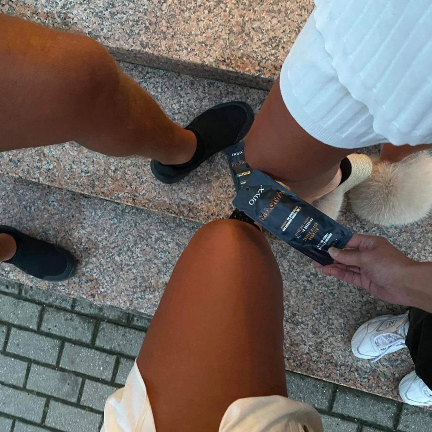 Frau mit glitzerndem Nageldesign hält Onyx Magma Triple Black Bronzer vor einem Solarium, zeigt elegantes Detailbild für Indoor-Tanning