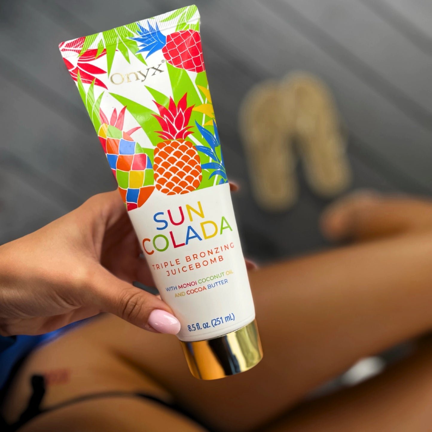 Hand hält Suncolada Bräunungslotion, Hintergrund verschwommen