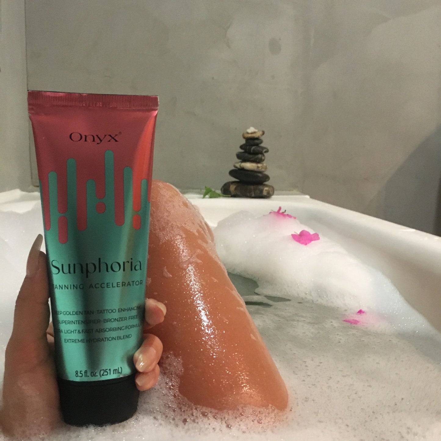 Onyx Sunphoria Bräunungslotion in einer Badewanne mit Schaum und Blumen