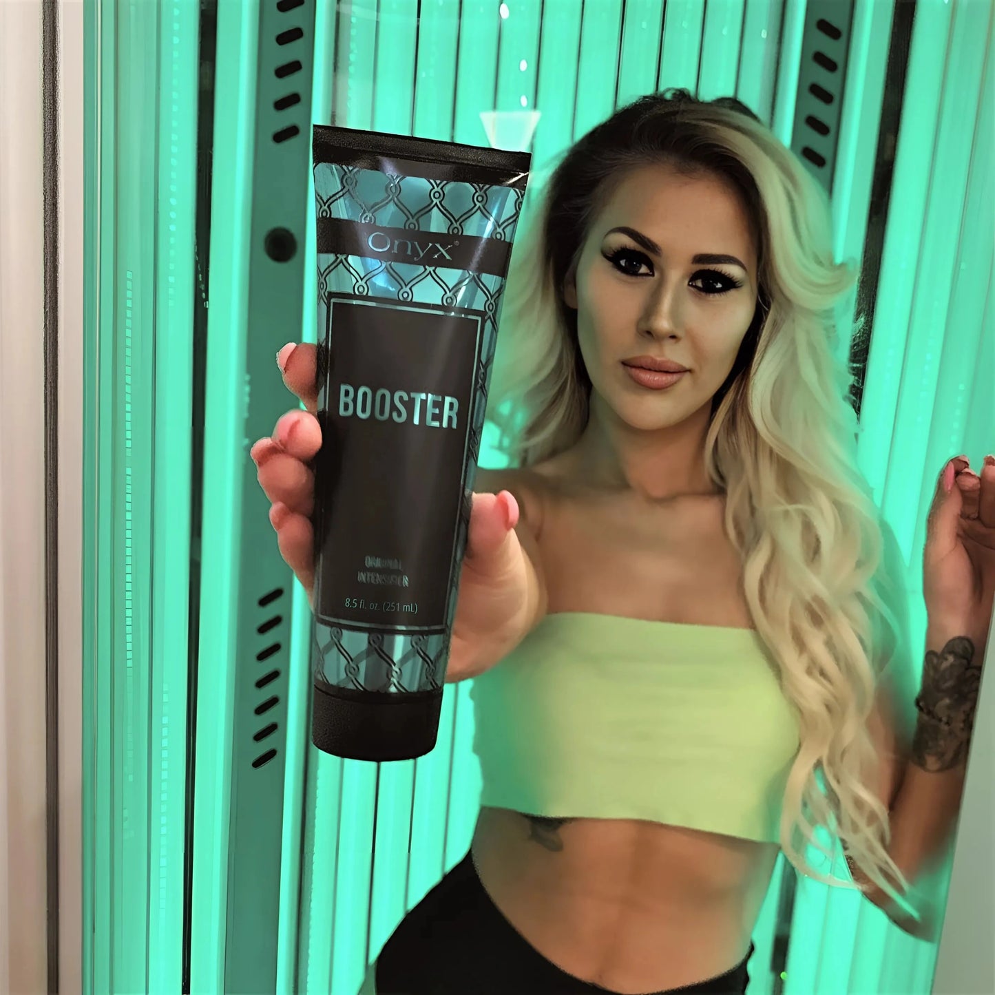 Blonde Frau in Sonnenbank hält Onyx Tanning Booster Lotion direkt vor die Kamera, ideale Szene für Indoor-Bräunung mit stylischem Auftritt