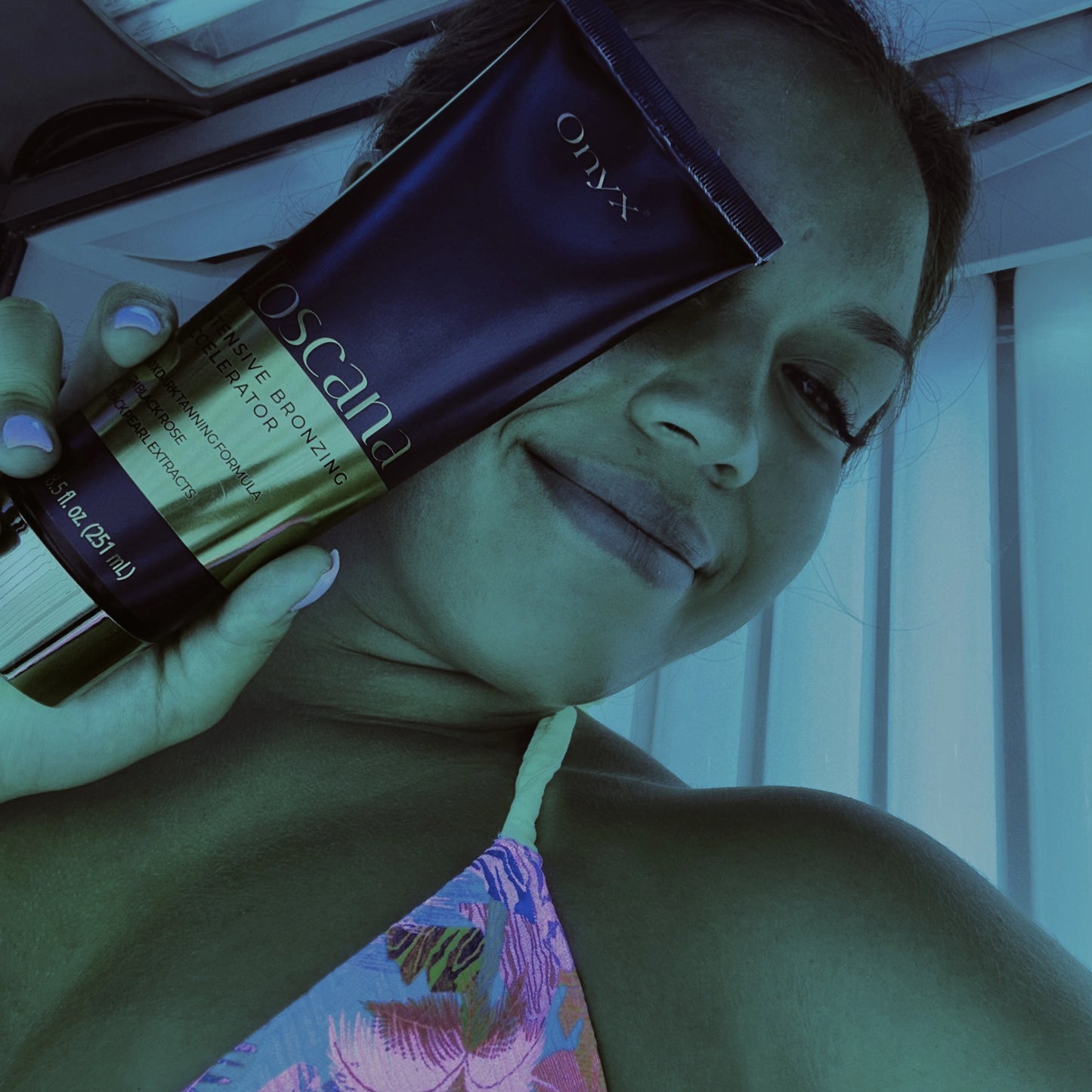 Frau lächelt und hält Onyx Toscana Bräunungslotion vor Gesicht im Solarium unter blauem Licht