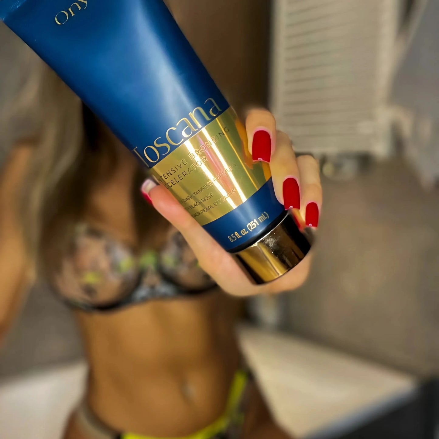 Unschärfe im Hintergrund, Fokus auf Onyx Toscana Lotion in Hand mit roten Nägeln