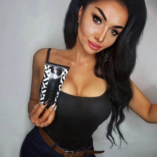 Frau mit langem schwarzen Haar hält die Onyx Black Porcelain Lotion vor hellem Hintergrund, elegant und glamourös