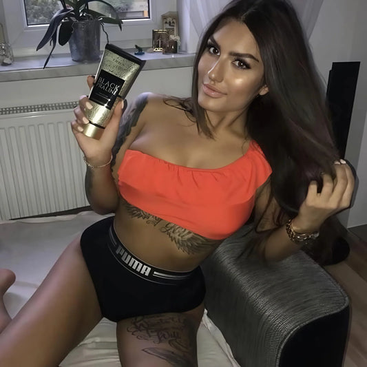 Frau mit schwarzem Sporttop hält Onyx Black Praline Lotion direkt zur Kamera