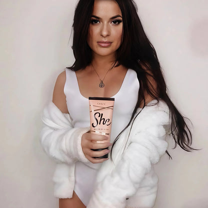 Frau in weissem Body mit langem dunklem Haar haelt Onyx She Lotion in der Hand, ideale Loesung fuer eine glamouroese, gepflegte Braeune