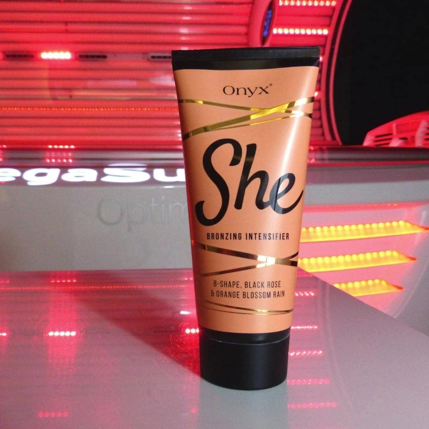 Onyx She Braeunungslotion steht auf einer roten Solariumflaeche – elegante Verpackung und intensive Formel fuer Frauen, die Haut und Braeune pflegen moechten